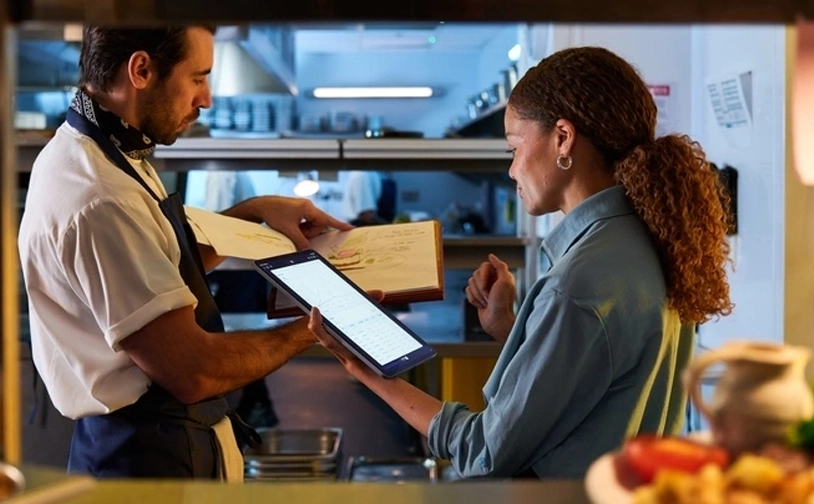 Restaurant staff taking an order using a digital tablet at a professional kitchen pass