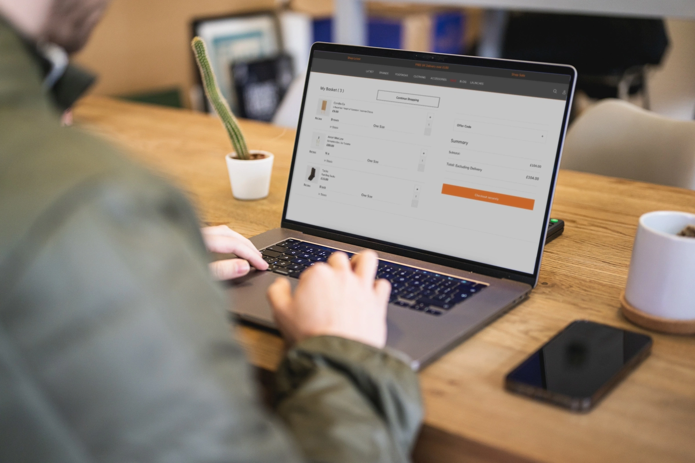 Person shopping online for ceramic vases and home décor using a laptop while holding a credit card.