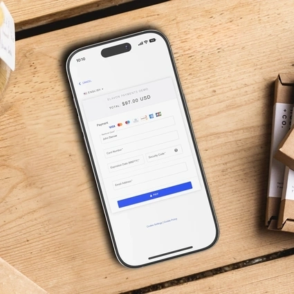 Smartphone on a wooden surface showing an online payment form with card details fields and a 'Pay' button—representing digital transactions where AI can help prevent fraud
